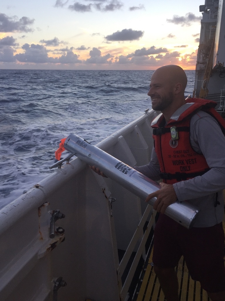 Visiting scientist Joe Fader from Duke University deploys a sonobuoy at sunset. This short-term drifting buoy contains a hydrophone that detects and transmits the low frequency sounds of baleen whales that might be in the area. Photo: NOAA Fisheries/Ali Bayless.